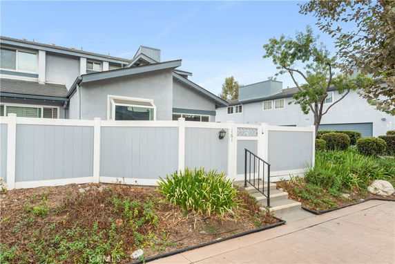 Front view of a house with a fenced yard and steps leading to the entrance.