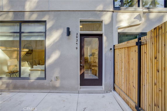 Front view of a modern house entrance with large windows and a wooden fence.