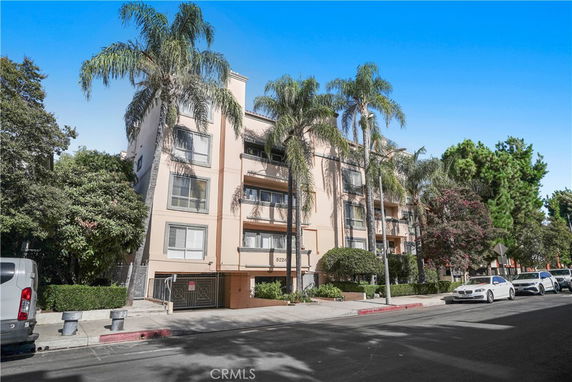 Front view of a multi-story residential building with palm trees.