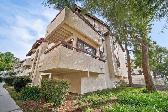Front view of a multi-story building with balconies and stucco exterior.