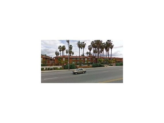 Front view of a two-story residential building with palm trees nearby.