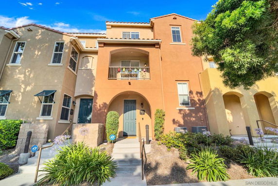 Front view of a multi-story townhouse with a central entrance and balcony.