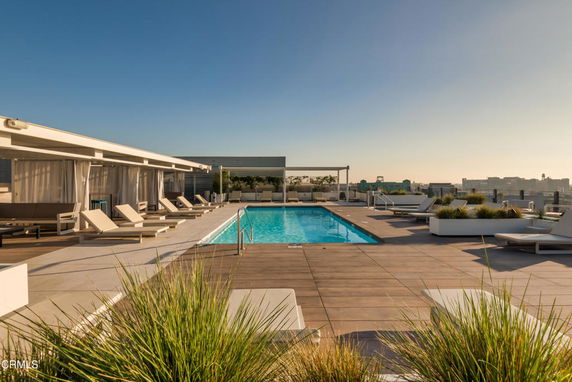 Rooftop swimming pool with lounge chairs and cabanas.