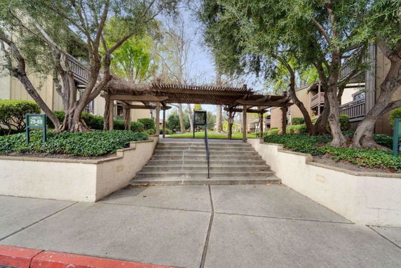 Front view of a residential building with stairs and a pergola.