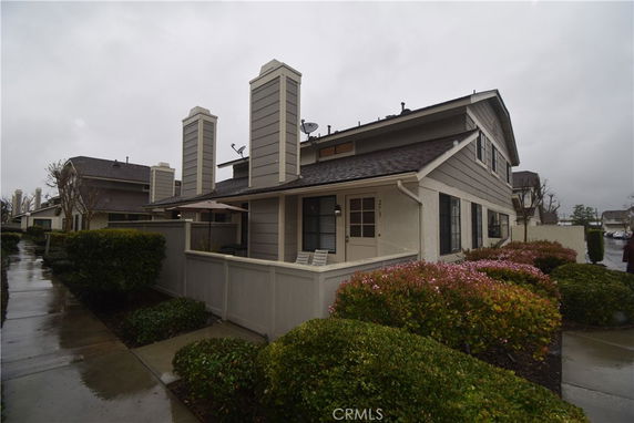 Front view of a two-story house with a fenced patio area.