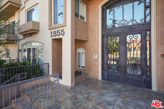 Front view of a building entrance with decorative metal doors and the number 1255 displayed.