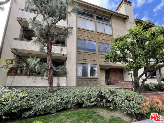 Front view of a multi-story residential building with balconies and large windows.