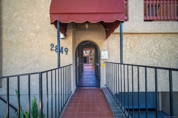 Front view of a building entrance with a red canopy and metal gate.