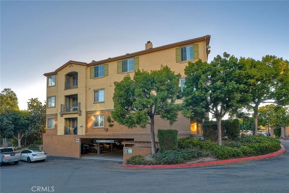 Front view of a multi-story apartment building with attached parking.