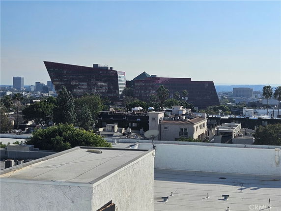 Panoramic view of cityscape with modern buildings in the distance and residential rooftops in the foreground.