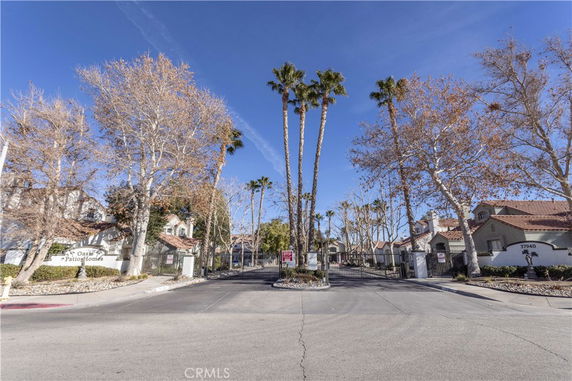 Front view of a gated residential community with trees and multiple houses.
