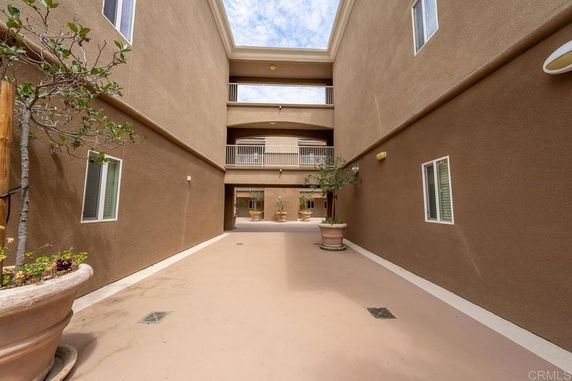 Open walkway between buildings with potted plants and balconies above.