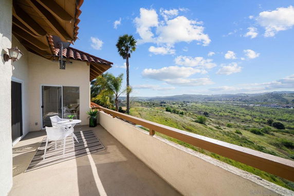 Outdoor balcony space with seating, overlooking a scenic landscape.
