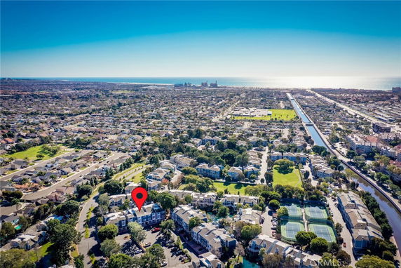Aerial view of a residential neighborhood with a canal and distant ocean.
