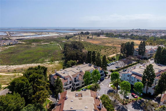 Panoramic view of residential buildings with open fields and bodies of water in the background.