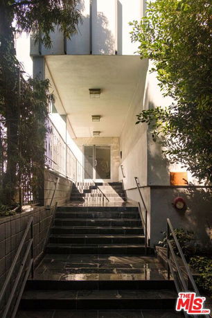 Entrance of a building with a staircase leading to a glass door.