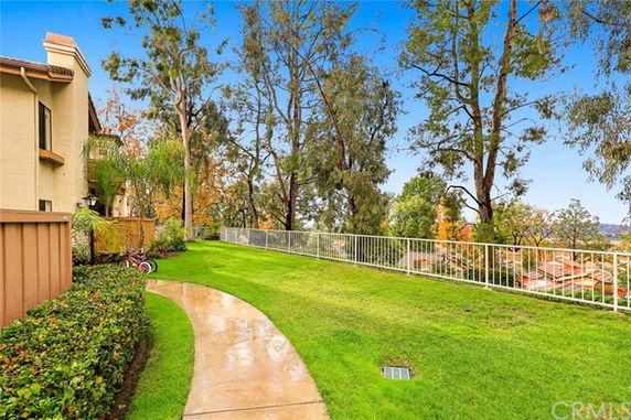 View of a grassy area with trees and a fence overlooking rooftops.