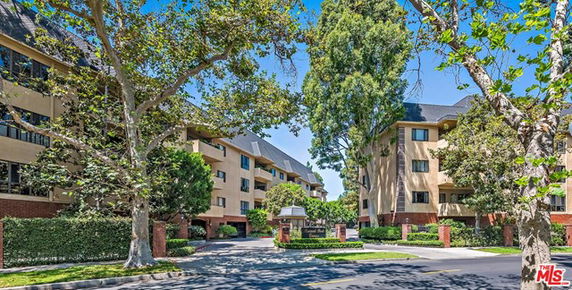 Front view of a multi-story residential building with adjacent trees.