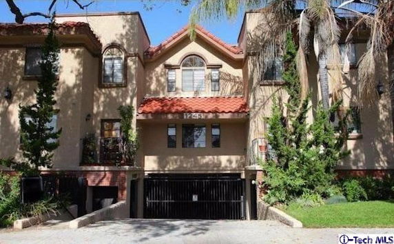 Front view of a multi-story house with a gabled roof and arched window.