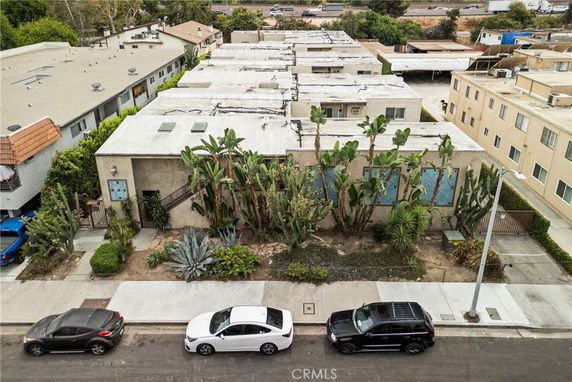 Front view of a flat-roofed building with desert plants in the front yard.