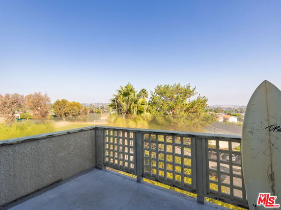 Balcony with a view of surrounding trees and distant landscape.