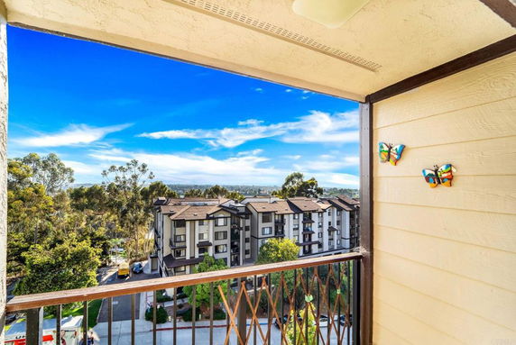 View from a balcony overlooking a multi-story apartment complex and trees.