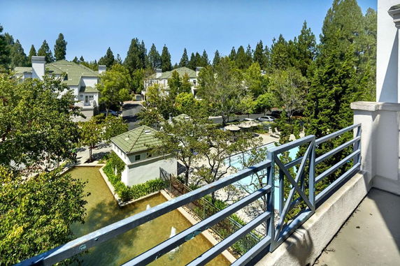 Panoramic view from a building balcony showing surrounding houses and greenery.