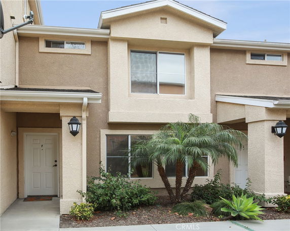 Front view of a two-story townhouse with a small porch and white door.