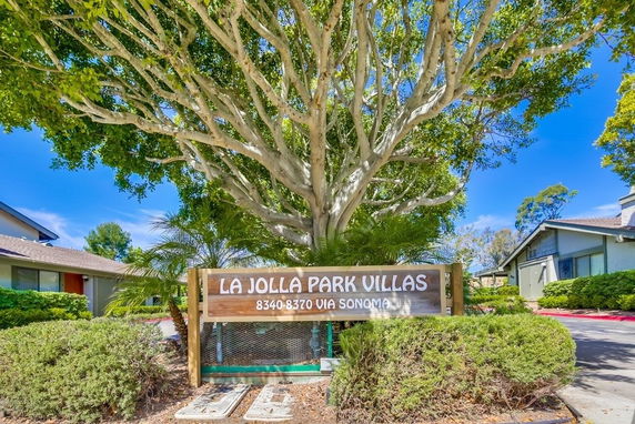 Front view of residential buildings with a large tree and sign reading 'La Jolla Park Villas'.