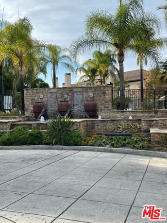 Front view of a building entrance with a stone wall and fountains, named Siena.