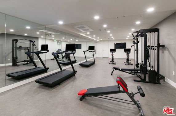Indoor gym area equipped with treadmills, stationary bikes, and weight machines.