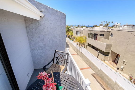 View from a balcony overlooking nearby buildings and a distant ocean.