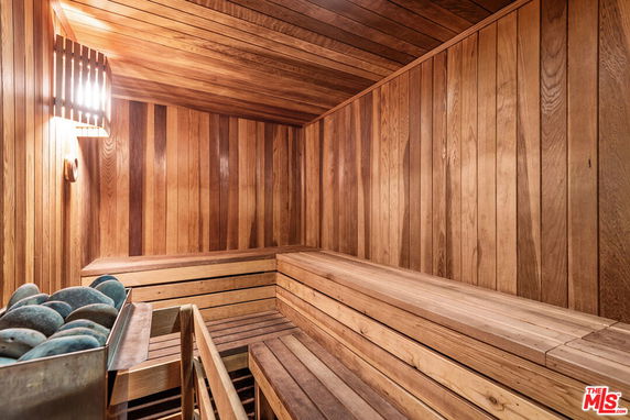 Interior view of a wooden sauna room with benches and a heater with stones.