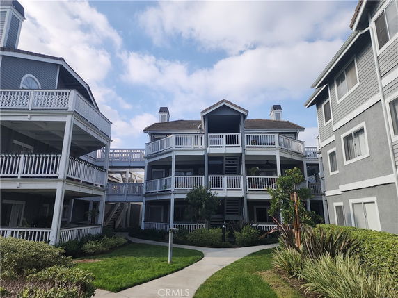 Front view of a multi-story residential building with balconies and railing.