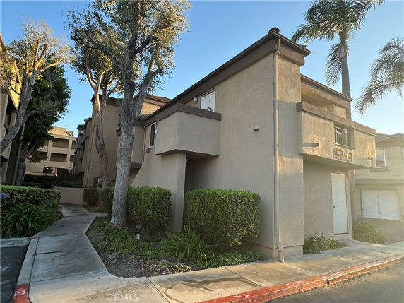 Front view of a multi-story building with balconies and a walkway.