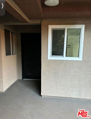 Front entrance area of a residential building with a door and windows.