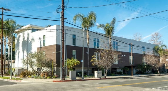 Front view of a modern multi-story building with a flat roof and large windows.