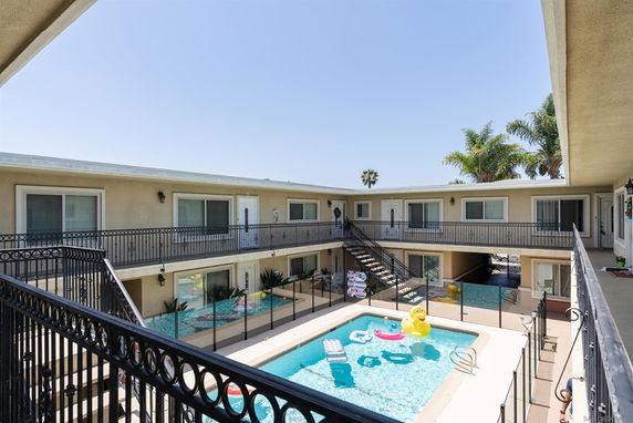 Courtyard view of an apartment complex with a central swimming pool and two levels of pathways.