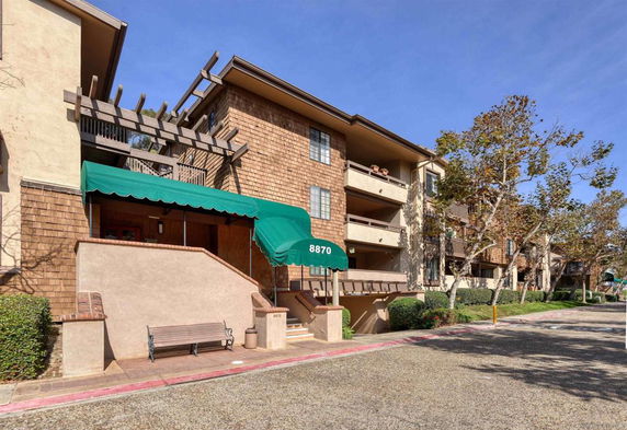 Front view of a multistory apartment building with balconies and green awnings.