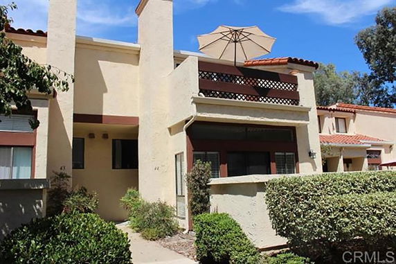 Front view of a two-story house with a balcony and umbrella.