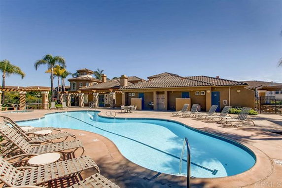 Outdoor swimming pool with lounge chairs and a building in the background.