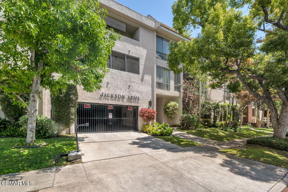 Front view of a multi-story apartment building with a gated entrance.
