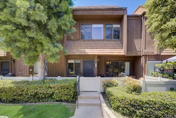 Front view of a two-story house with wooden facade and shrubbery in front.