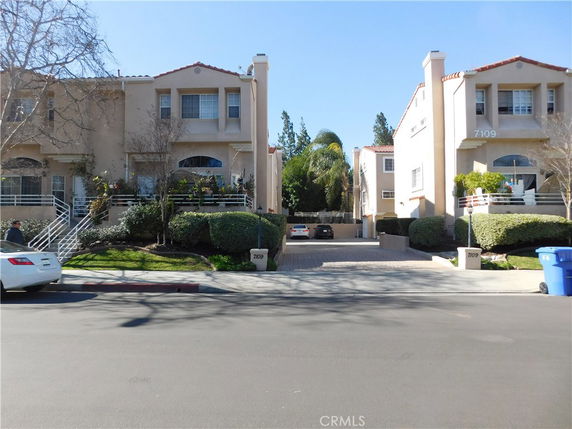 Front view of a multi-story building with driveways and garages.