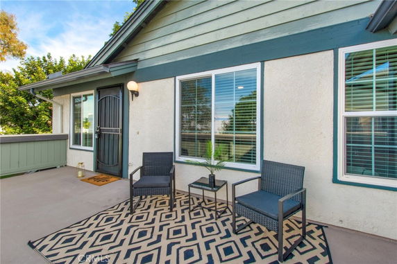 Front view of a house with a small patio area featuring two chairs and a small table.