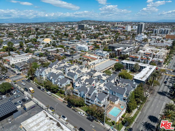 Aerial view of a cityscape featuring residential buildings, roads, and a swimming pool.