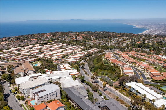Panoramic view of a coastal residential area with houses and apartments, overlooking the ocean.