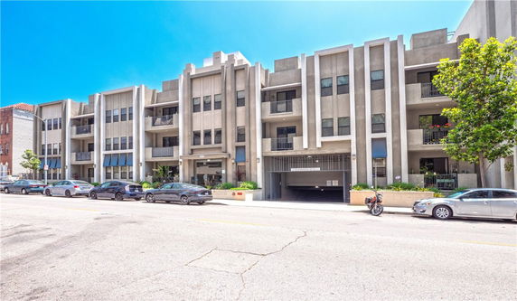 Front view of a multi-story apartment building with balconies and an entrance.