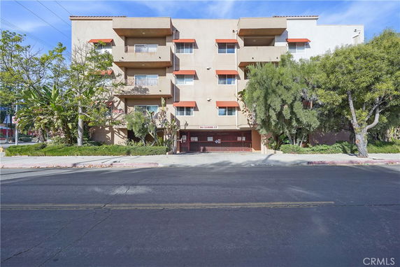 Front view of a multi-story apartment building with balconies and brown awnings.