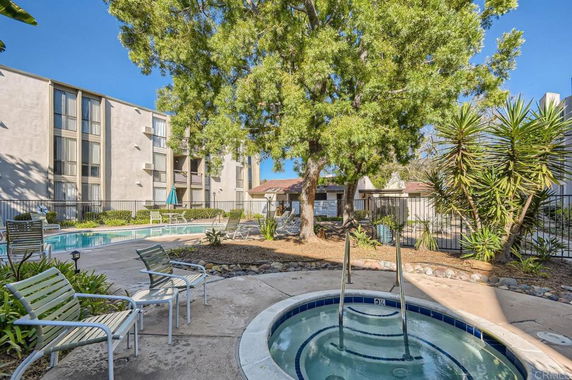 Outdoor swimming pool area with a hot tub and surrounding seating.